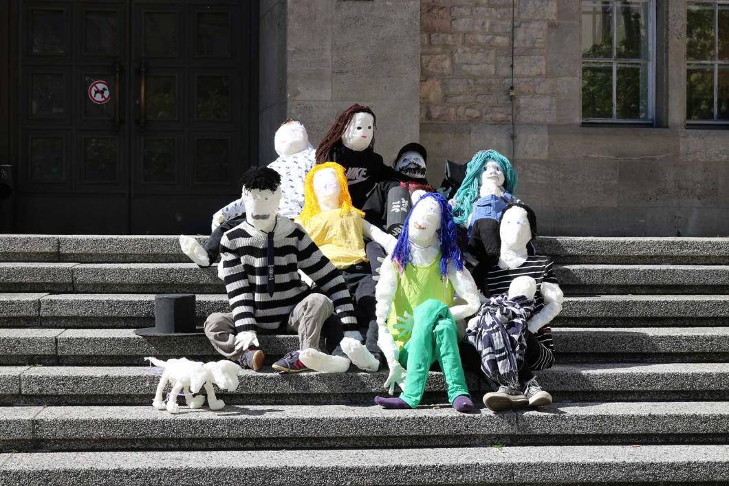 Eine Menschengruppe mit Hund aus Styropor, auf Stufen sitzend
